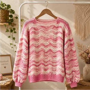 May include: A long-sleeved crochet sweater featuring a wavy, horizontal striped pattern in alternating shades of bright pink, light pink, and cream. The garment has a round neckline, ribbed cuffs, and a ribbed hem, all crafted in a solid pink.