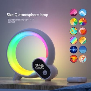 May include: A white Size Q atmosphere lamp with a rainbow-colored light ring. The lamp has a digital clock display and a remote control. The text on the lamp says "Support mobile phone APP control".
