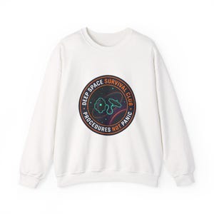 May include: White crewneck sweatshirt with a circular graphic. The graphic reads "Deep Space Survival Club" around the edge, with an illustration of a spaceship and planets in the center. The text "Procedures Not Panic" is also included.