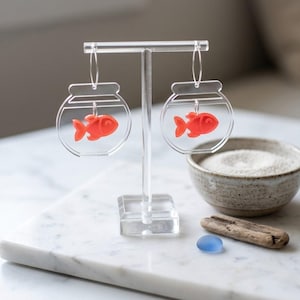 Könnte beinhalten: Ein Set aus drei Keramikbechern mit gesprenkelter, matter Oberfläche. Die Becher sind in den Farbtönen Creme, Hellgrau und Dunkelgrau gehalten. Jeder Becher hat ein schlichtes, minimalistisches Design und einen abgerundeten Henkel.