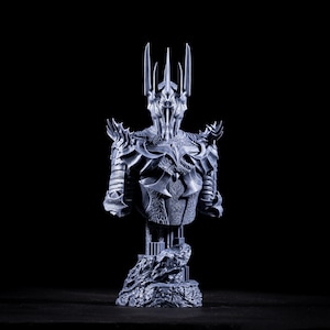 Puede incluir: Un busto gris de un personaje de fantas&iacute;a impreso en 3D que lleva una corona y una armadura. El busto est&aacute; sobre una base rocosa.