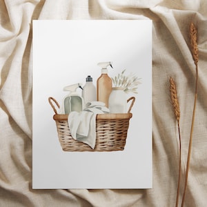 May include: A wicker basket filled with cleaning supplies, including spray bottles, a white towel, and a small vase with dried flowers. The basket is on a white background.