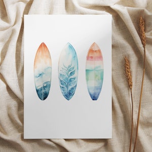 May include: Three watercolor paintings of surfboards with different designs. The surfboards are painted in shades of blue, green, and orange.