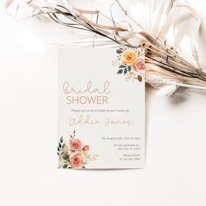 May include: A white card with a floral design and the text "bridal shower" in pink script. The card also includes the text "Please join us for a bridal shower honoring Addie Jones" and details about the event.