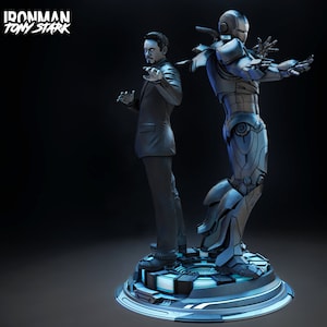 Puede incluir: Una figura de acción de Iron Man plateada y azul con un acabado metálico. La figura está de pie sobre una base circular con un diseño azul y plateado. La figura está posada con los brazos extendidos y la cabeza ligeramente inclinada hacia un lado. La figura está de pie junto a un hombre con traje. El texto "IRONMAN TONY STARK" es visible en la esquina superior izquierda de la imagen.