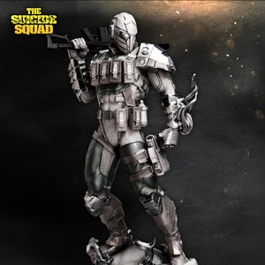Può includere: Una action figure bianca e grigia di un personaggio di The Suicide Squad, che tiene una pistola. La figura indossa un casco con visiera e una tuta tattica con tasche e cinghie.