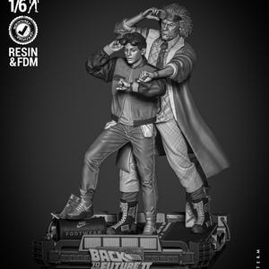 Peut inclure: Modèle imprimé en 3D en niveaux de gris de Doc Brown et Marty McFly du film Retour vers le futur 2. Le modèle est à l'échelle 1/6 et représente Doc Brown tenant une paire de lunettes et Marty McFly les mains en position de combat. Le modèle est posé sur une plateforme sur laquelle sont imprimés les mots "Retour vers le futur 2".