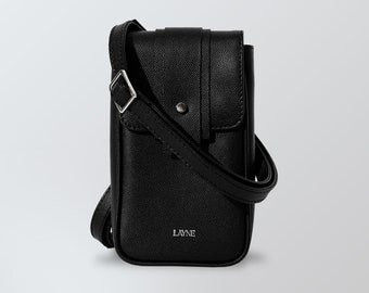 Può includere: Borsa a tracolla per telefono in pelle nera con cinturino regolabile e fibbia in metallo argentato. La borsa ha una chiusura a lembo con un bottone in metallo argentato e la parola "LAYNE" impressa sul davanti.
