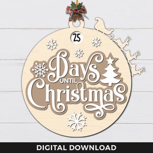 May include: A wooden Christmas countdown ornament shaped like a circle with a brown background and white lettering. The ornament says "Days Until Christmas" with a small Christmas tree and snowflakes. The ornament has a number 25 on it and a string for hanging.