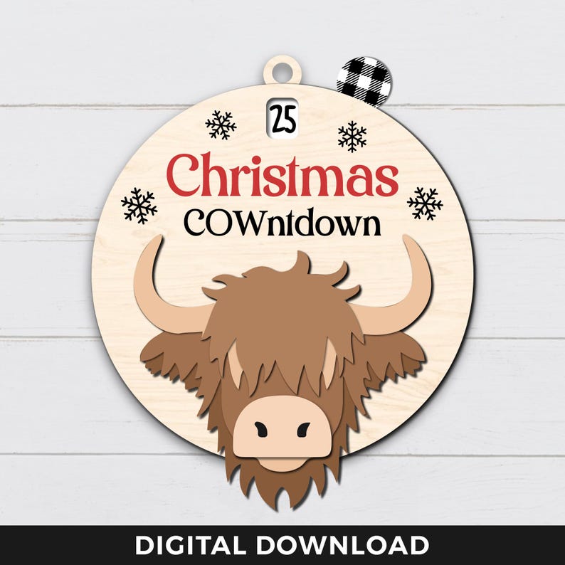 May include: A round wooden ornament featuring a brown Highland cow head illustration. The ornament has the text "25 Christmas COWntdown" printed on it.