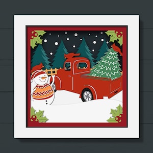May include: A red pickup truck with a Christmas tree in the back, driving through a snowy forest. A snowman with a red hat and orange scarf stands in the snow. The scene is depicted in a paper cut-out style.