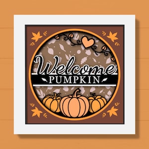 Può includere: Un cartello a tema autunnale incorniciato con le parole "Welcome Pumpkin" in un carattere decorativo. Il cartello presenta zucche, foglie e un cuore nei toni dell'arancione, del marrone e del bianco. La cornice è bianca.