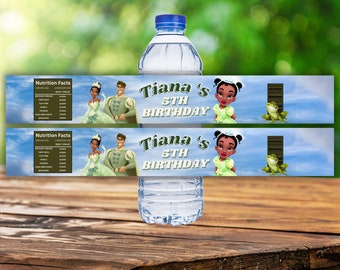 Puede incluir: Dos etiquetas para botellas de agua con Tiana y el Príncipe Naveen de La Princesa y el Sapo de Disney. Las etiquetas son azules y verdes con una etiqueta de información nutricional en el lado izquierdo y el texto "Tiana's 5th Birthday" en el lado derecho.
