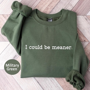 May include: Military green sweatshirt with the text "I could be meaner" in white. The sweatshirt has a crew neck and long sleeves. The color is described as military green.