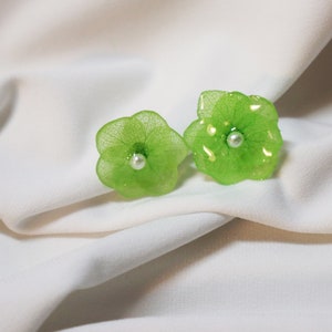 Peut inclure: Une paire de boucles d'oreilles en forme de fleur verte avec un accent de perle au centre de chaque fleur.