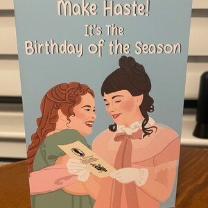 May include: A light blue card with the text "Make Haste! It's The Birthday of the Season" in white. Two women in period dress are depicted holding a letter.