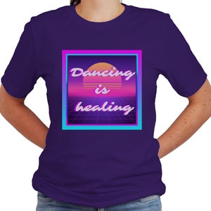 May include: Purple t-shirt with a retro-style graphic that says "Dancing is healing" in a pink and blue box.