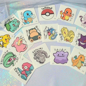 May include: A set of 13 colourful Pokemon temporary tattoos featuring various characters from the popular anime series. The tattoos are printed on clear sheets and are ready to be applied to skin. The tattoos include characters such as Pikachu, Bulbasaur, Charmander, Squirtle, and more.