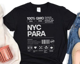 May include: Black t-shirt with white text that reads "100% GMO FREE REAL Contents may vary in accent, vibe and beliefs NYC PARA INGREDIENTS Organic hustle, educated, caffeinated, dedicated, a whole lot of patience, a dash of sweetness and a hint of gangsta, no cup added. TOUGH MADE WITH EXPRESSIVE HANDLE REQUIRES LOVE WITH RESPECT CAFFEINE"