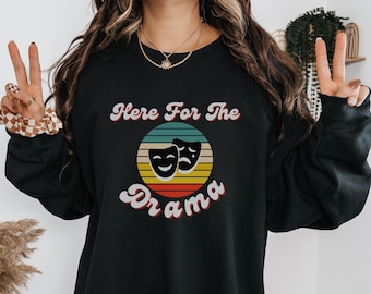 May include: Black sweatshirt with a retro-style graphic that says "Here For The Drama" with two theater masks in a circle.