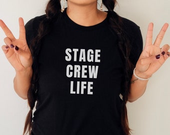 May include: A black t-shirt with the text "STAGE CREW LIFE" printed in white on the front.