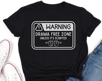 May include: Black t-shirt with a white warning sign that says "Drama Free Zone Unless It's Scripted" with two white theater masks.