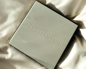 May include: A sage green hardcover journal with the text "Our Book of Memories" embossed on the front cover.