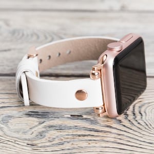 May include: White leather watch band with rose gold hardware and a rose gold Apple Watch.