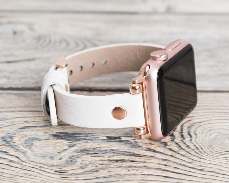 May include: White leather watch band with rose gold hardware and a rose gold Apple Watch.