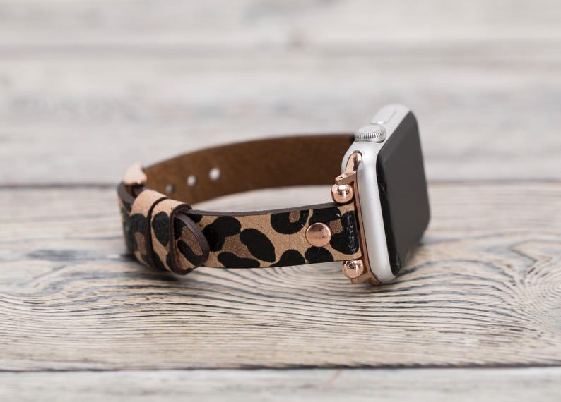 May include: A brown leather Apple Watch band with a leopard print pattern and rose gold accents.