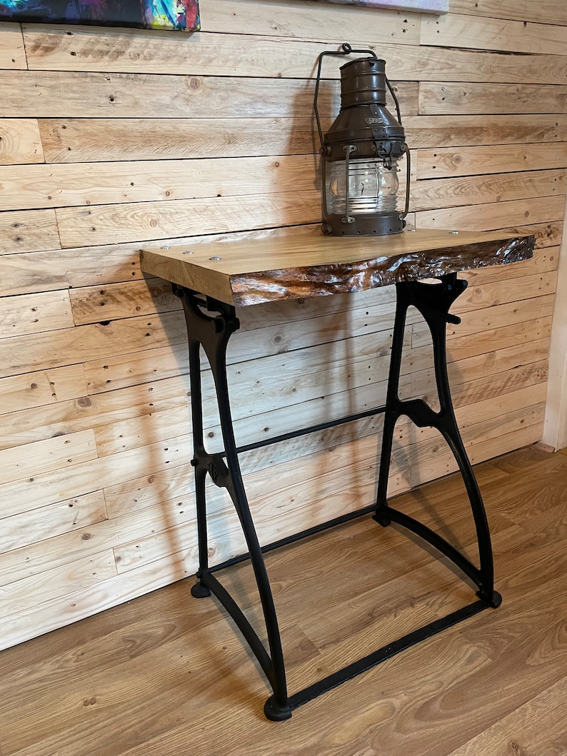 May include: A rustic wooden table with a live edge top and black metal legs. The table is made from reclaimed wood and has a natural finish. A vintage oil lamp sits on the table.