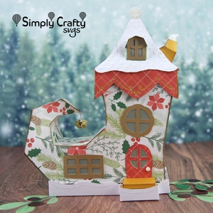 May include: A festive Christmas elf shoe house with a red door, white roof, and a bell hanging from the top. The house is decorated with a holly and poinsettia pattern.