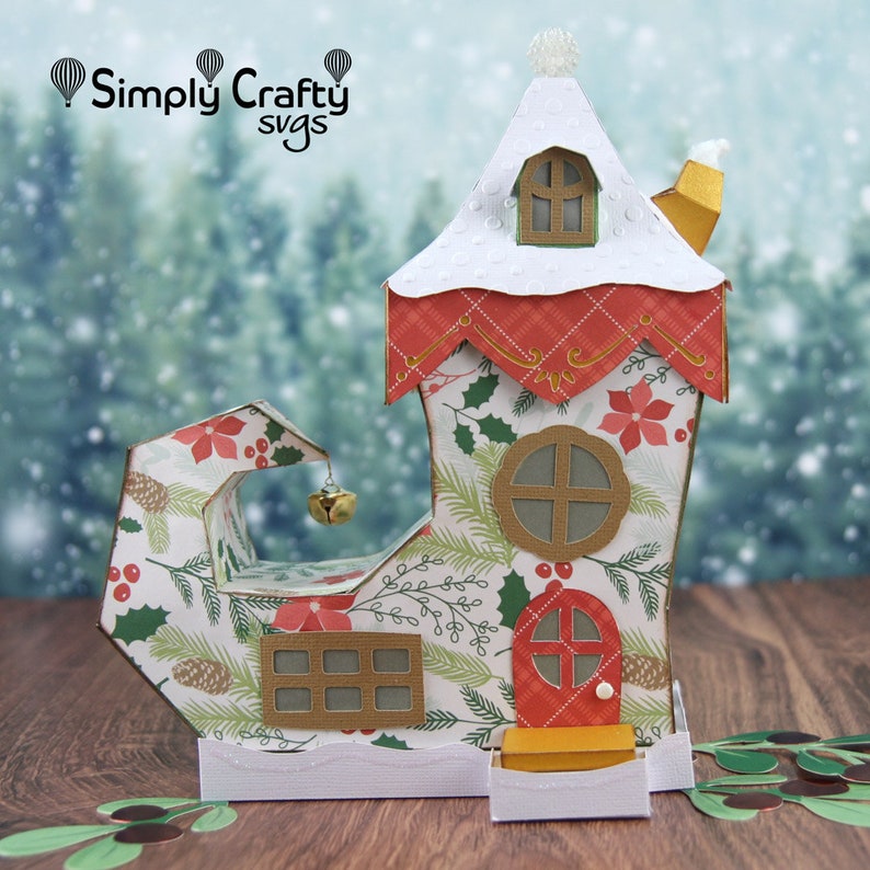 May include: A festive Christmas elf shoe house with a red door, white roof, and a bell hanging from the top. The house is decorated with a holly and poinsettia pattern.