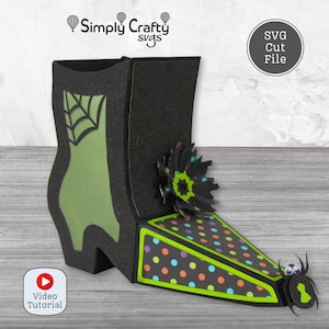 May include: A black and green paper witch boot with a spider and flower embellishments. The boot features a green silhouette with a spiderweb design and a polka-dot pattern on the toe. The text "Simply Crafty svgs" and "SVG Cut File" are visible.