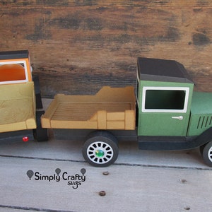 Peut inclure: Un mod&egrave;le de camion vintage en papier, fait de carton vert et noir. Le camion a une cabine noire avec une carrosserie verte et une fen&ecirc;tre blanche. Le camion a une benne en bois avec une surface brune. Le camion a quatre roues avec des pneus noirs et des enjoliveurs verts. Le camion est sur une surface en bois.