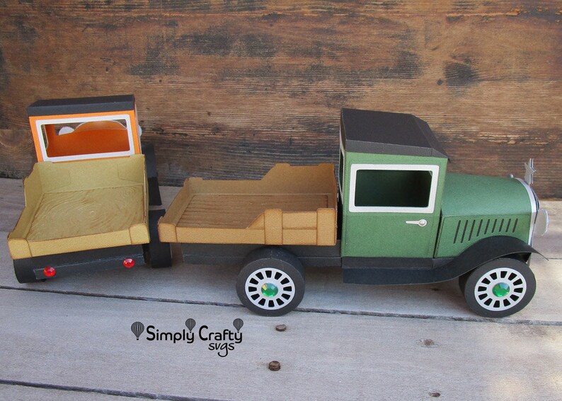 Peut inclure: Un mod&egrave;le de camion vintage en papier, fait de carton vert et noir. Le camion a une cabine noire avec une carrosserie verte et une fen&ecirc;tre blanche. Le camion a une benne en bois avec une surface brune. Le camion a quatre roues avec des pneus noirs et des enjoliveurs verts. Le camion est sur une surface en bois.