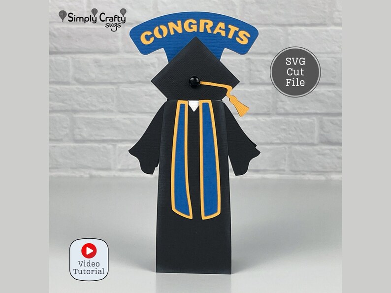 Pode incluir: Um chap&eacute;u e uma beca de gradua&ccedil;&atilde;o pretos com uma faixa azul e dourada. O chap&eacute;u tem uma borla dourada. A beca tem um colarinho branco. O chap&eacute;u &eacute; coroado com uma faixa azul e amarela que diz "CONGRATS".