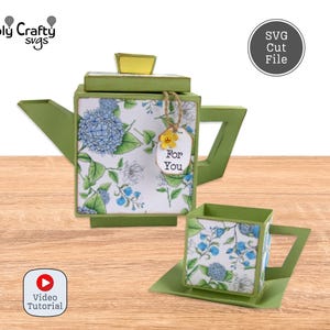 Könnte beinhalten: Ein grünes Papier-Tee-Set mit Blumendesigns und dem Schriftzug "For You" auf einem Anhänger. Die Teekanne hat einen gelben Deckel, und die Tasse steht auf einer passenden Untertasse. Das Bild enthält auch ein Video-Tutorial-Symbol.