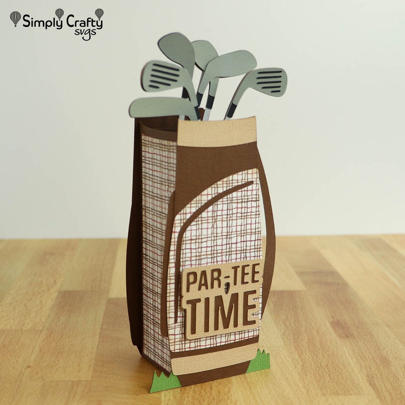 May include: A brown and tan golf bag with a plaid pattern and a green base. The bag is filled with gray golf clubs and has a sign that says "Par-Tee Time".