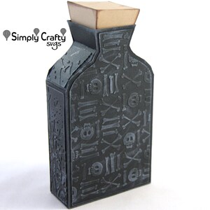 May include: A black papercraft bottle with a tan square stopper, featuring a repeating embossed pattern of skulls and crossbones. The text Simply Crafty svgs is printed in black above the bottle on the left side.