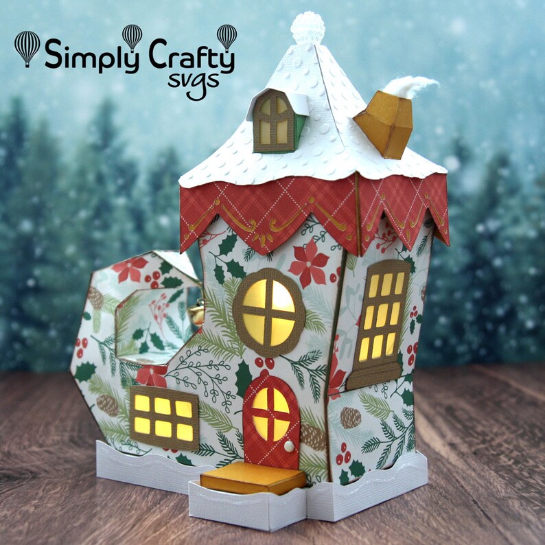 May include: A papercraft Christmas boot house with a snowy roof, a chimney, and windows with lights. The boot is decorated with a holly and pine pattern.