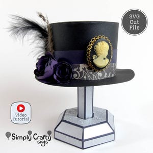 May include: A black top hat with a decorative cameo, purple ribbon, and floral accents. The hat is displayed on a silver stand. The image includes the text "SVG Cut File" and "Video Tutorial".