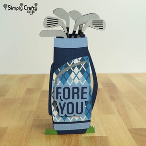 May include: A blue and white golf bag with golf clubs sticking out of the top. The bag has a plaid pattern and the words "FORE YOU" are on the front.