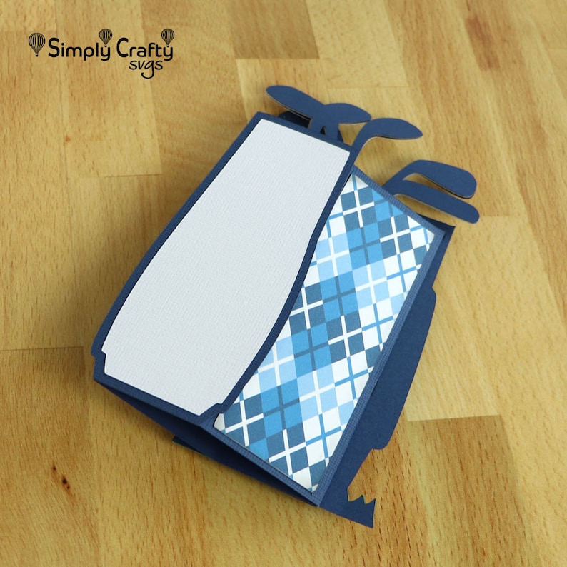 May include: A blue and white golf bag card with a plaid pattern and a white interior. The card is folded and has a pop-up design.