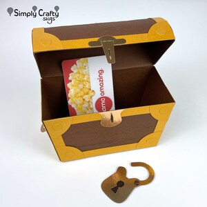 May include: A gold treasure chest with a brown wooden lid is open, revealing a gift card inside. The chest has a gold lock and key. The gift card is for AMC Cinemas and says "amo amazing".