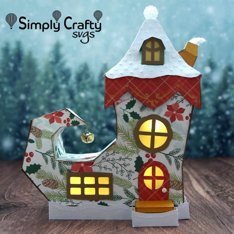 May include: A festive elf shoe house with a red roof, white snow, and a bell hanging from the toe. The house has windows with glowing lights and a red door. The shoe is decorated with a green and white Christmas pattern.