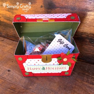 May include: A red and white polka dot treasure chest box with a green lid, a gold lock, and a red poinsettia flower. The box is open and contains a clear plastic bag with sweets and a white card that says "Gift Card". The box also has a green banner that says "Happy Holidays".