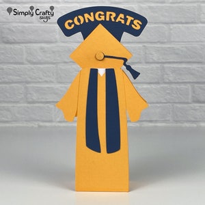 Pode incluir: Um chap&eacute;u e uma beca de gradua&ccedil;&atilde;o amarelos com uma faixa azul e a palavra "CONGRATS" no topo. A figura &eacute; feita de papel.