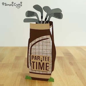 May include: A brown and tan golf bag with a plaid pattern and a green grass base. The bag is filled with gray golf clubs and has a brown sign that says "Par-Tee Time".
