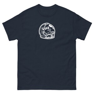 May include: A navy blue t-shirt with a white astronaut helmet graphic. The helmet has the text "LOS DEL ESPACIO" on it.